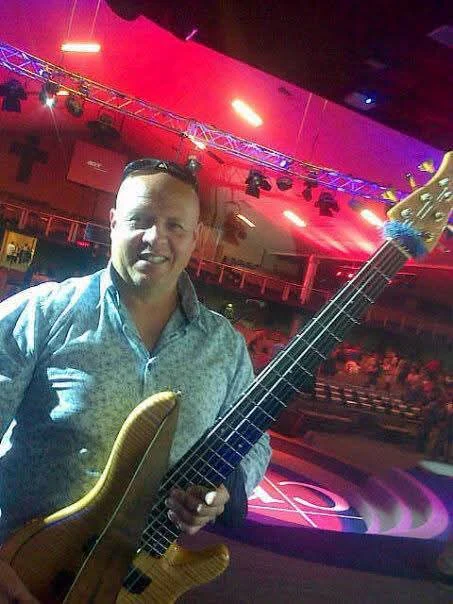 Lowell Jeffery with his five-string bass on a church stage under pink and red stage lights